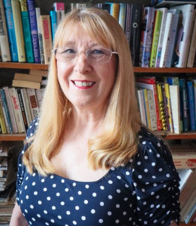 Susan seated at her writing desk in front of a bookshelf