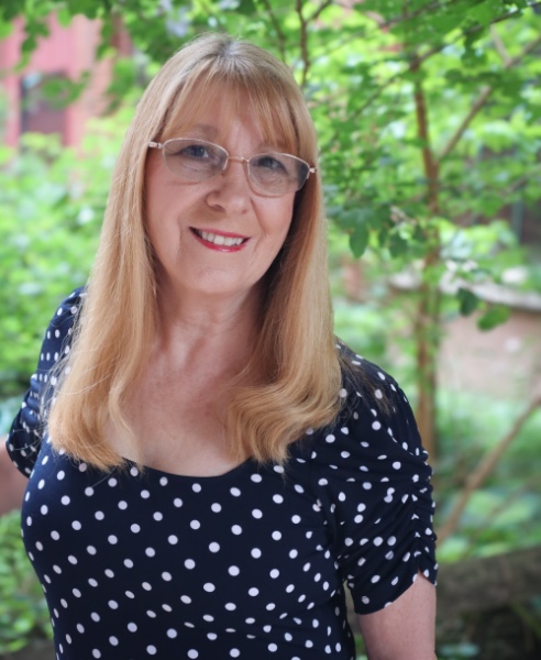 Susan smiling outdoors, surrounded by greenery